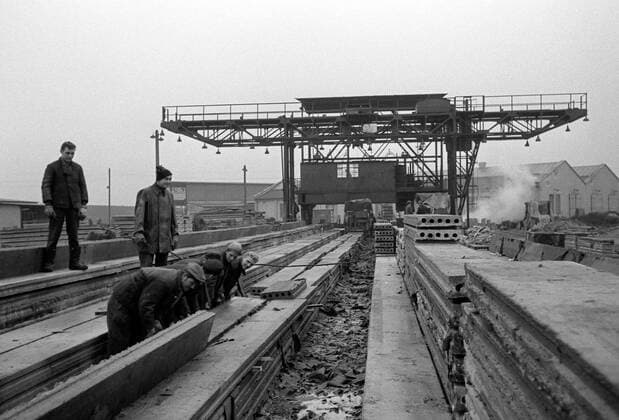Betonwerk Steinbruch DDR Historisches Bild und Foto: Arbeitern in einem Betonwerk. Produktion von Bohlen fuer den Strassenbau und fuer den Kolonnenweg der deutsch-deutschen innerdeutschen Grenze Berliner Mauer. Historical Image and Photography: Concrete Factory GDR