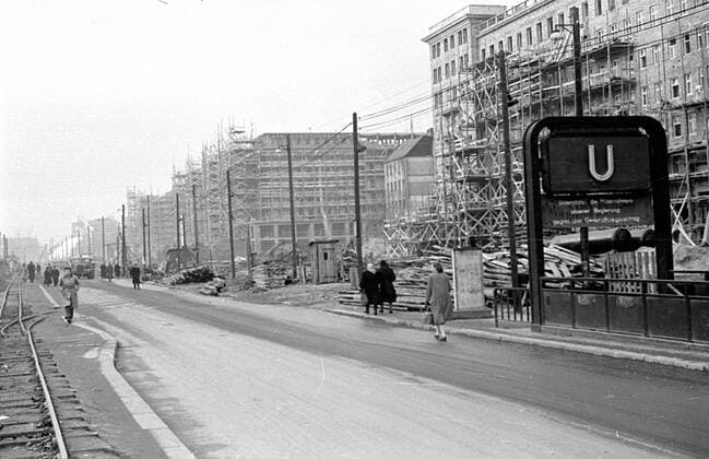 U-Bahnhof Weberwiese Berlin 1953 Historisches Bild und Foto: Berliner Karl-Marx-Allee früher Stalinallee im Vordergrund U-Bahnhof Marchlewskistrasse (heute Weberwiese). Kontext: Bau, Umbau der Stalinallee im Jahr 1953 nach den Visionen des Sozialistischen Realismus bzw. der Nationalen Bautradition. VEB Industriebau. Errichtung der Arbeiterpalaeste. Die Strasse, Boulevard wurde zwischen 1949 und 1961 Stalinallee (Große Frankfurter Straße) genannt und war das Vorzeigeprojekt im Rahmen des Ostdeutschen Wiederaufbauprogamms nach dem zweiten Weltkrieg. Die Stalinallee wurde in mehreren Stufen von den Architekten Hermann Henselmann, Hartmann, Hopp, Leucht, Paulick entwickelt. Platziert wurden Appartements, Aafes und ein Kino (International).