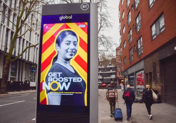 December 18, 2021, London, United Kingdom: People walk past an electronic screen urging everyone to get a booster vaccine in central London, as the Omicron variant of COVID-19 spreads in the UK. London United Kingdom - ZUMAs197 20211218_zaa_s197_023 Copyright: xVukxValcicx