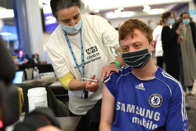 News Bilder des Tages December 18, 2021, London, United Kingdom: Chris White, 27 year old Chelsea fan, is being vaccinated by a member of the NHS vaccination team at the Chelsea stadium..The Chelsea Stamford Stadium was used as an NHS vaccination centre providing a marathon of jabs ˜Jabathon™. Bookings began from 10am as members of the military and NHS provided the vaccination. London United Kingdom - ZUMAs197 20211218_zaa_s197_129 Copyright: xBelindaxJiaox