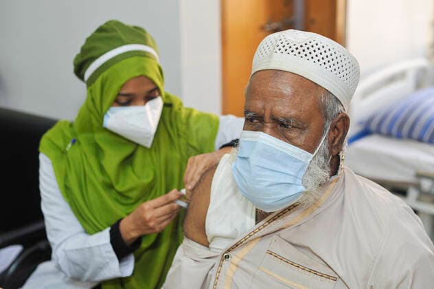 December 20, 2021: 20 December 2021 Sylhet, Bangladesh: A medical staff vaccinating an old age man with the PFIZER Covid-19 Vaccine 2nd dose at the M A G Osmani medical college & hospital vaccination center in Sylhet. Meanwhile, in Dhaka city of Bangladesh launched the COVID-19 booster shot campaign from Sunday with Pfizer vaccine to scale up its efforts for containing the spread of the lethal virus. - ZUMAr143 20211220_zap_r143_005 Copyright: xMdxRafayatxHaquexKhanx