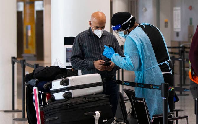 (211221) -- MISSISSAUGA (CANADA), Dec. 21, 2021 -- A medical worker wearing personal protective equipment helps an international traveler at Toronto Pearson International Airport in Mississauga, Ontario, Canada, on Dec. 21, 2021. Canada reported 9,597 new COVID-19 cases Tuesday afternoon, bringing the cumulative total to 1,907,180 cases with 30,082 deaths, according to CTV. (Photo by Xinhua) CANADA-MISSISSAUGA-COVID-19-CASES-1.9 MLN ZouxZheng