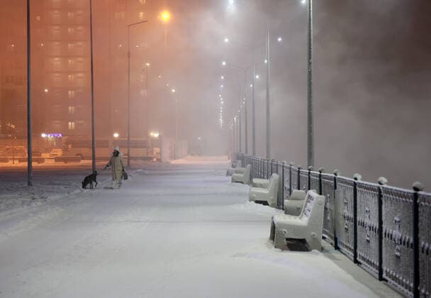 News Themen der Woche KW51 News Bilder des Tages KRASNOYARSK, RUSSIA - DECEMBER 22, 2021: A woman and a dog walk by the Yenisei River; the air temperature is -22Â°C (-7.6Â°F). The Yenisei River stopped freezing in winter after the construction of the Krasnoyarsk Dam. Andrei Samsonov TASS  TS11CDD2