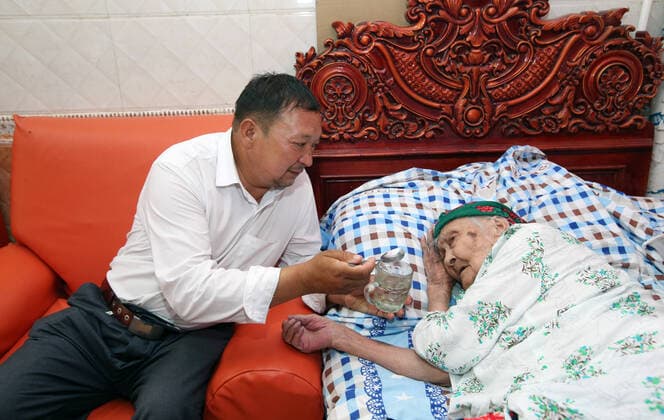 KASHGAR, CHINA - JUNE 29: Alimihan Seyiti (R) lies on bed while her grandson looks after her on June 29, 2021 in Kashgar, Xinjiang Uygur Autonomous Region of China. Alimihan Seyiti, the oldest person in China, passed away on December 16 at the age of 135 in Xinjiang.  Copyright: xVCGx CFP111362201386