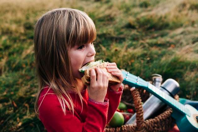 IMAGO Creative: Jahreszeit Frühling, Picknick Blond girl eating sandwich on grass model released, ASGF01670