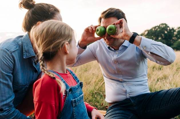 Father covering eyes with fruits while playing with daughter at park model released, ASGF01690