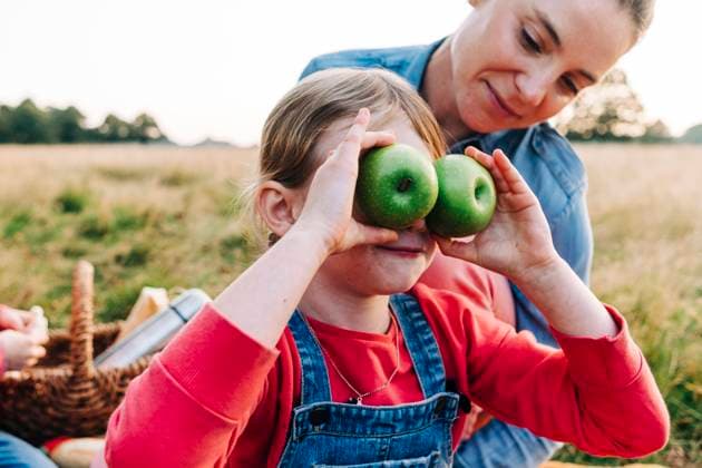 Mother looking at daughter playing with fruits in park model released, ASGF01692