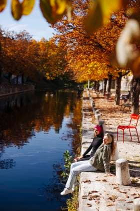 IMAGO Creative, Jahreszeit Herbst, Ferien Teenage friends sitting at canal on sunny day model released, DAWF02308