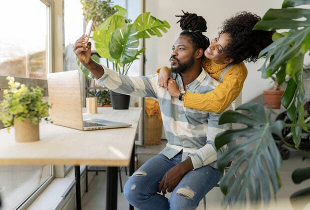 IMAGO Creative: Digitale Welt, Social Commerce Man puckering and influencing with girlfriend embracing at home model released property released, JCCMF04612