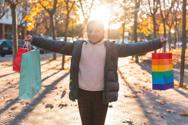 IMAGO Creative: Pride Month 2022, Engagement der Jugendlichen Smiling girl holding shopping bags on footpath model released, JAQF00960