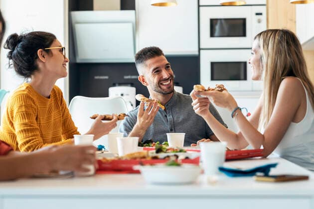 IMAGO Creative: Gesellschaft, Integration Smiling businessman with pizza talking to businesswoman at office cafeteria model released property released, JSRF01725