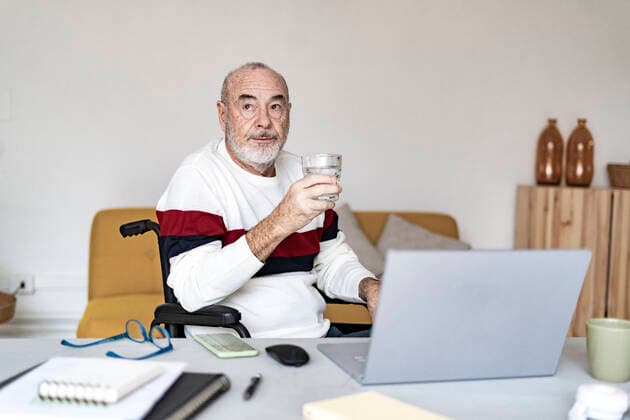 Disabled businessman holding drinking glass at home model released property released, GIOF14349