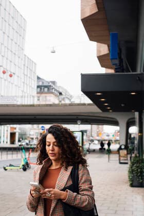 IMAGO Creative: Internationaler Frauentag, Mental Load und Care-Arbeit Female entrepreneur text messaging on smart phone on street Sweden, Stockholm, model released Copyright: xMaskotx , MA91174