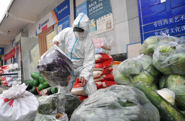 (220105) -- XI AN, Jan. 5, 2022 -- Volunteer Li Guang carry vegetables at Deshan shared kitchen in Yanta District of Xi an, northwest China s Shaanxi Province, Jan. 5, 2022. Located in Yanta District of Xi an, Deshan shared kitchen was run as an anti-cancer kitchen , providing convenience for cancer patients and their families to cook meals. Xu Kai, founder of the shared kitchen, transformed this anti-cancer kitchen into a fight-against-epidemic kitchen after the city has been hit by the recent COVID-19 resurgence. Up to now, more than 30 volunteers have joined the food delivery activities of the kitchen to help not only cancer patients and their families who are stranded in Xi an, but also some personnel who work for the prevention 