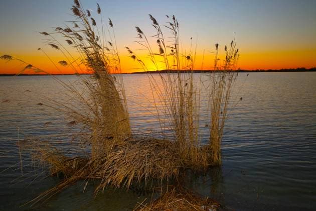 Blick am Donnerstag (06.01.2022) in Verchen (Landkreis Mecklenburgische Seenplatte) auf einen Sonnenuntergang am Kummerower See. Der See ist mit einer Fläche von fast 33 Quadratkilometern und einer mittleren Tiefe von 8,1 Metern der viertgrößte See des Landes Mecklenburg Vorpommern und achtgrößte innerhalb Deutschlands. An seinen Ufern sind in den zurückliegenden Jahren zahlreiche Angebote für Segler, Surfer und Wasserwanderer entstanden. Dazu gibt es eine einmalige Naturlandschaft und gemütliche Unterkünfte für Gäste. Sie locken inzwischen auch immer mehr Touristen an den See. Doch momentan sind die Strände verwaist und liegen die Boote auf dem Trockenen. Dennoch lohnt sich auch zu dieser Jahreszeit ein Spaziergang entlang der Strände und