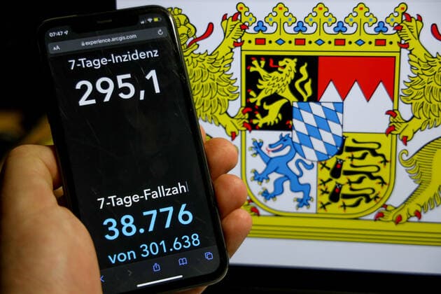 Coronavirus in Deutschland - Covid-19-Dashboard des Robert Koch-Institut DEU, Deutschland, Bayern 09.01.2022: Die 7-Tage-Inzidenz für das Bundesland (Fälle letzte 7 Tage 100.000 EW) wird auf einem iPhone angezeigt, im Hintergrund das Landeswappen