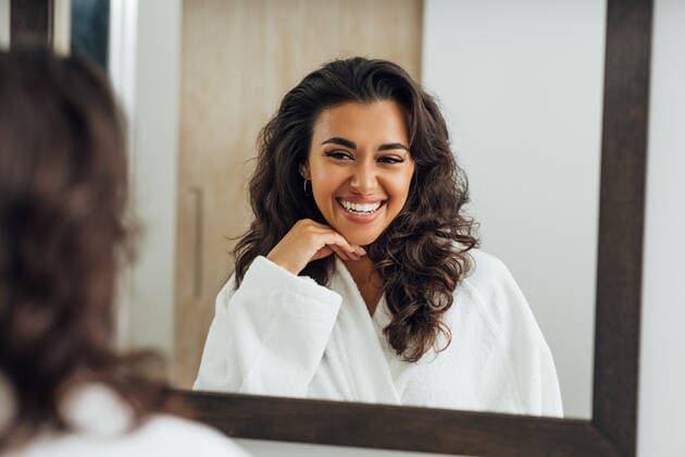Reflection of a brunette woman in bathroom mirror touching hair Copyright: xxArtemxVarnitsinx