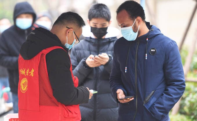 (220110) -- ZHENGZHOU, Jan. 10, 2022 -- A volunteer helps a foreigner register for COVID-19 tests at a testing site in Zhengzhou, central China s Henan Province, Jan. 10, 2022. The city has carried out rounds of all-inclusive nucleic acid testing to help curb the spread of COVID-19. ) CHINA-HENAN-ZHENGZHOU-COVID-19-TEST (CN) ZhangxHaoran 