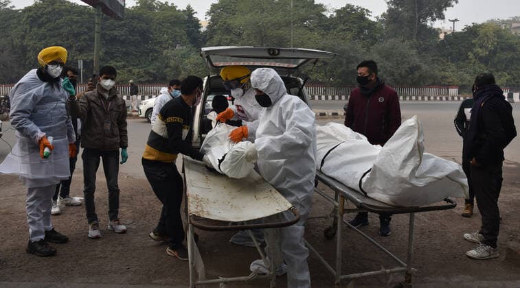 NEW DELHI, INDIA - JANUARY 13: Shaheed Bhagat Singh Sewa Dal volunteers in personal protective equipment (PPE) take out from a hearse the body of a person who died due to the Covid-19 coronavirus, at a cremation ground at crematorium Center Old Seema Puri Ghat, on January 13, 2022 in New Delhi, India. (Photo by Sonu Mehta Hindustan Times ) Daily Life Amid Coronavirus Pandemic In India