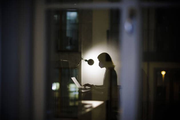 Symbolfoto zum Thema Maske am Arbeitsplatz. Eine Frau sitzt abends in ihrem Schreibtisch im Buero und traegt eine FFP2 Maske. Berlin, 14.01.2022 Berlin Deutschland