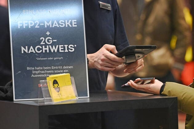 Bayern kippt 2G-Regel im Einzelhandel Archivfoto; Kontrolle der 2G Regel im Einzelhandel in Bayern. Ein Schild am Eingang eines Geschaeftes weist auf die 2G Regel hin.Einlass nur mit FFP2 Maske und 2g Nachweis,Impfnachweis und Ausweisdokument bereithalten, Ein Mitarbeiter kontrolliert vor dem Eintreten die 2G Regel -geimpft, genesen. Eintritt nur fuer geimpfte oder genesene Kunden,Personen, Impfnachweis und Personalausweis bereithalten. Smartphone,Handy.