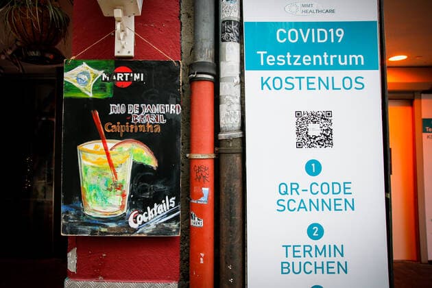 Eine Tafel einer Bar, auf welchem fâˆöÂºr Caipirinha Cocktails geworben wird, steht neben dem Hinweisschild eines Covid-19 Testzentrums in der Altstadt von Duesseldorf, 19.01.2022. Duesseldorf Deutschland Copyright: xLeonxKuegeler photothek.dex