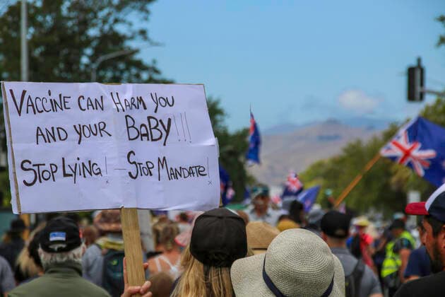 January 22, 2022, Christchurch, Canterbury, New Zealand: A protester marches down Papanui Rd. with a placard during the antivax protest..Protesters take to the streets in the affluent suburb of Merivale in protest against the mandatory Covid19 vaccination. Christchurch New Zealand - ZUMAs197 20220122_zaa_s197_024 Copyright: xAdamxBradleyx