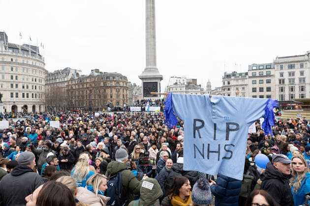 January 22, 2022, London, England, United Kingdom: Protestors seen rallying at Trafalgar Square, with a torn NHS uniform hung on a cross that says RIP NHS during the demonstration..By April 2022, 100k members of the NHS will have to be fully vaccinated or lose their jobs. In light of this draconian requirement, NHS nurses have come together to protest against such coercion, defending their medical freedom and accusing the government for a total mistreatment of the health workers over the pandemic. Other anti-lockdown and anti-vaccine groups have jointly protested against the restrictions imposed by the government, and threaten to take to the streets should the restrictions not be lifted by 27th Jan 2022. London United Kingdom - ZUMAs197 20220122_zaa_s197_145 Copyright: xBelindaxJlaox