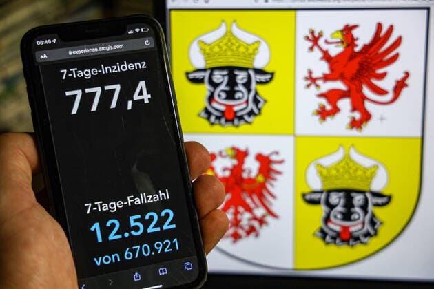 Coronavirus in Deutschland - Covid-19-Dashboard des Robert Koch-Institut DEU, Deutschland, Mecklenburg-Vorpommern 23.01.2022: Die 7-Tage-Inzidenz für das Bundesland (Fälle letzte 7 Tage 100.000 EW) wird auf einem iPhone angezeigt, im Hintergrund das Landeswappen