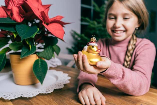 Smiling girl holding golden Christmas duck by star plant at home model released property released, KMKF01778