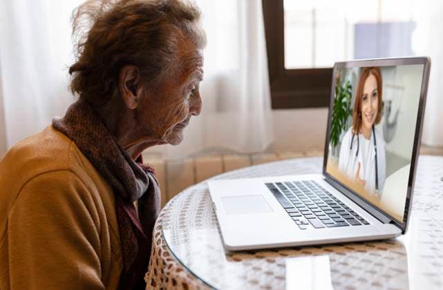 IMAGO Creative: 2022 Favoriten IMAGO Creative: Lokalhelden - Gesundheits- und Rettungskräfte Doctor discussing with senior woman on video call through laptop at home model released property released, JCCMF04935