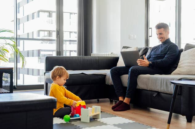 Father freelancing on laptop and son playing in living room model released property released, PGF00940