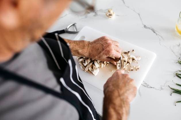 Man cutting mushrooms on cutting board at kitchen counter model released property released, JRFF05233