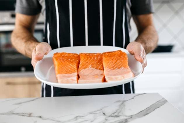Man holding plate with raw fish slices in kitchen at home model released property released, JRFF05249