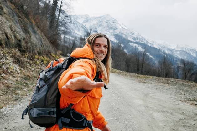 IMAGO Creative: 2022 Sport Favoriten IMAGO Creative: Wintersport, Urlaub Cheerful man in orange jacket walking on mountain road model released, OMIF00399