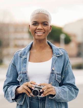 Smiling woman in denim jacket holding old camera model released, JCCMF05167