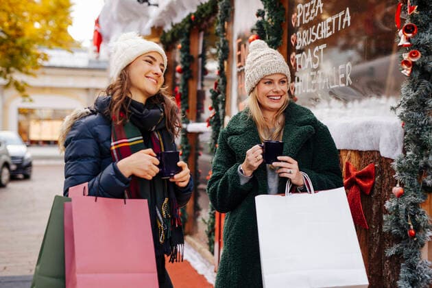 Smiling friends with shopping bags and mugs at Christmas market model released, DAWF02411