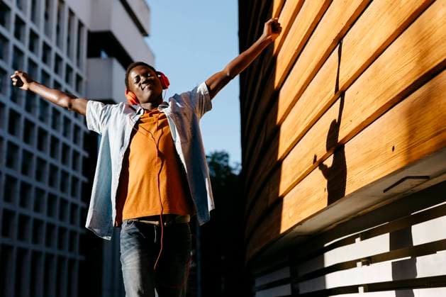 Cheerful man with arms outstretched enjoying music through headphones model released, TCEF02142