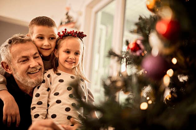 Grandchildren with grandfather looking at decorated christmas tree at home model released property released, ZEDF04422