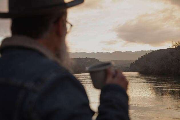 IMAGO Creative, Jahreszeit Herbst auf dem Land Back view of unrecognizable bearded male hiker in warm clothes drinking hot beverage while standing near lake during trekking on the sunset JordiCalvera_RiverSunset_2.jpg Copyright: xJordixCalverax Model Released