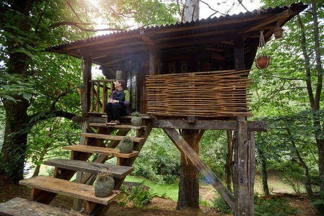 IMAGO Creative, Leben im Bamhaus Distant person sitting with mug with hot beverage in tree house with wooden ladder located amidst green plants in nature of Asturias in Spain, Model released, Property released RamonLopez_TreeHouseCountryside_12.jpg Copyright: xRamonxLopezx MR