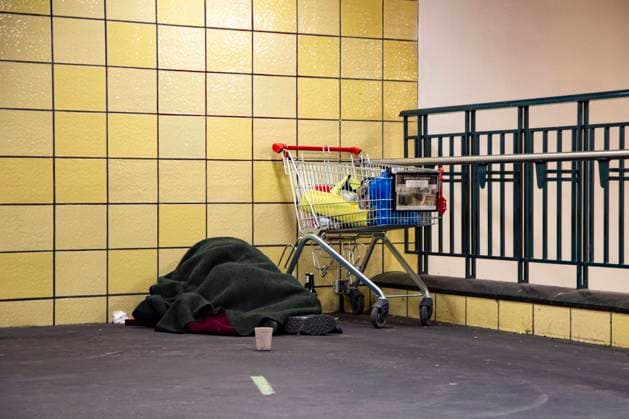 Ein Obdachloser schlaeft unter einer Decke bei einem Einkaufswagen am Bahnhof Frieedrichstrasse in Berlin am 25. Januar 2022. Armut in Berlin *** A homeless man sleeps under a blanket by a shopping cart at the Frieedrichstrasse train station in Berlin, Germany, January 25, 2022 Poverty in Berlin, Germany