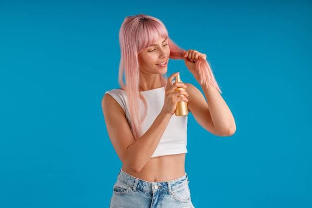 IMAGO Creative, Lifestyle, Barbiecore Caring young woman smiling and applying moisturizing spray to her smooth pink hair while standing isolated over blue studio background Caring young woman smiling and applying moisturizing spray to her smooth pink hair while standing isolated over blue studio background. Beauty products, hair care concept Copyright: xyaroslavxastakhovx 40848734
