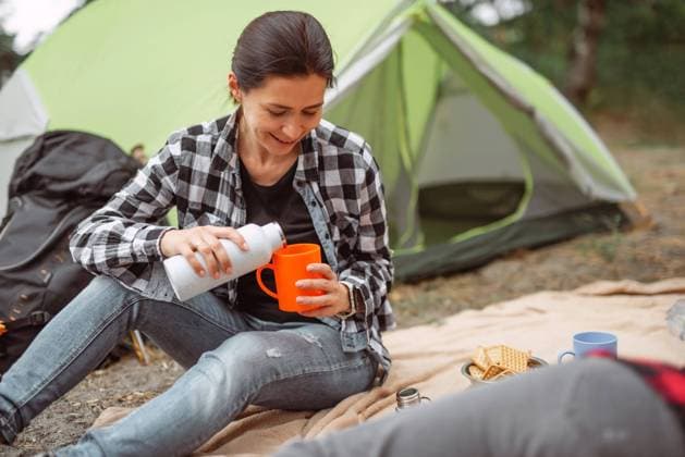 IMAGO Creative: Sommer, In den Bergen Camping in mountains forest Beautiful adult girl drinking tea in camping in forest with tent on background and smiling. Young woman traveller during hiking in mountains Copyright: xSKRYPKOxIEVGENx 43010612