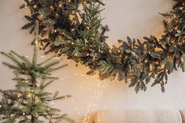 Beautiful fireplace with mirror and fur branches. View over decorated artificial fireplace with decorations inside. Handmade paper stars, candles inside. Beautiful coniferous wreath on the top of fireplace. Decorative round mirror over the fireplace. Copyright: xx 43119468