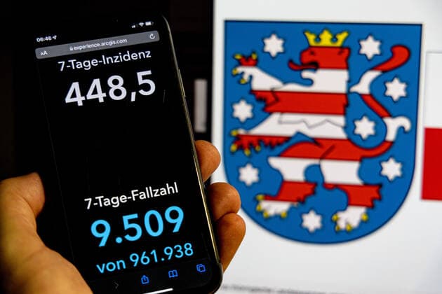 Coronavirus in Deutschland - Covid-19-Dashboard des Robert Koch-Institut DEU, Deutschland, Thüringen 30.01.2022: Die 7-Tage-Inzidenz für das Bundesland (Fälle letzte 7 Tage 100.000 EW) wird auf einem iPhone angezeigt, im Hintergrund das Landeswappen