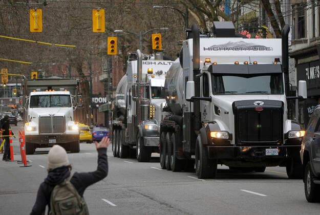 (220130) -- VANCOUVER, Jan. 30, 2022 -- A person gestures to vehicles on the street during a parade in support of Ottawa s Freedom Convoy trucker protest in downtown Vancouver, British Columbia, Canada, Jan. 29, 2022. Vehicles jammed downtown Vancouver streets Saturday to show their support of the Freedom Convoy of long-haul drivers to oppose the Canadian government s requirement that all cross-border essential workers, including truckers, must show proof of vaccination at a port of entry. (Photo by Xinhua) CANADA-VANCOUVER-FREEDOM CONVOY-SUPPORT-PARADE LiangxSen 