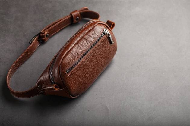 A brown belt bag made of textured brown leather on a black stone background. Elegant fanny pack brown bag with a zipper A brown belt bag made of textured brown leather on a black stone background. Elegant fanny pack brown bag with a zipper. Genuine leather, handmade. Banana bag Copyright: xAleksandrxGrechanyukx 44099120
