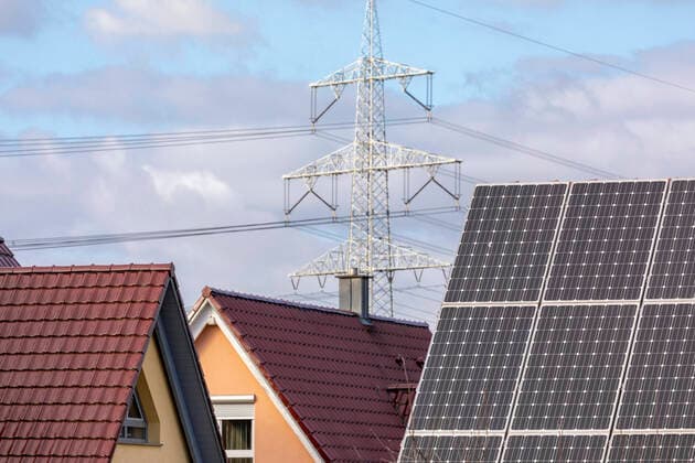 Wohnhäuser mit Photovoltaikanlagen, im Hintergrund ein großer Strommast Ausbau privater PV Anlagen, Fördergelder Erlangen Bayern Deutschland