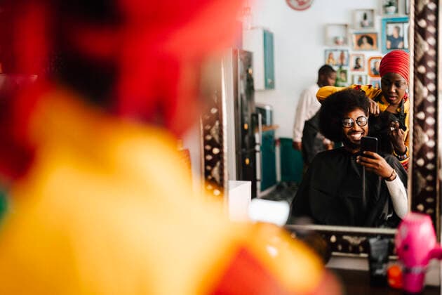 IMAGO Creative: Neue Aussichten Smiling male customer taking selfie while female hairdresser cutting his hair at barber shop Sweden, Stockholm, model released, property released Copyright: xMaskotx , MA91640